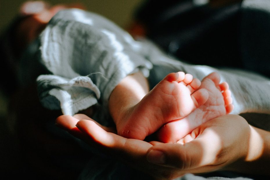 Mani che sorreggono i piedini di un neonato